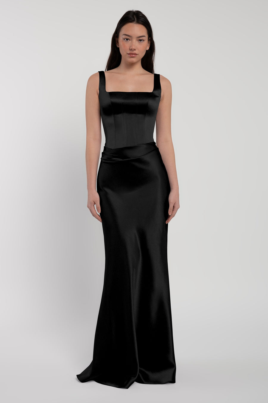 Woman wearing a black satin gown on a light gray background