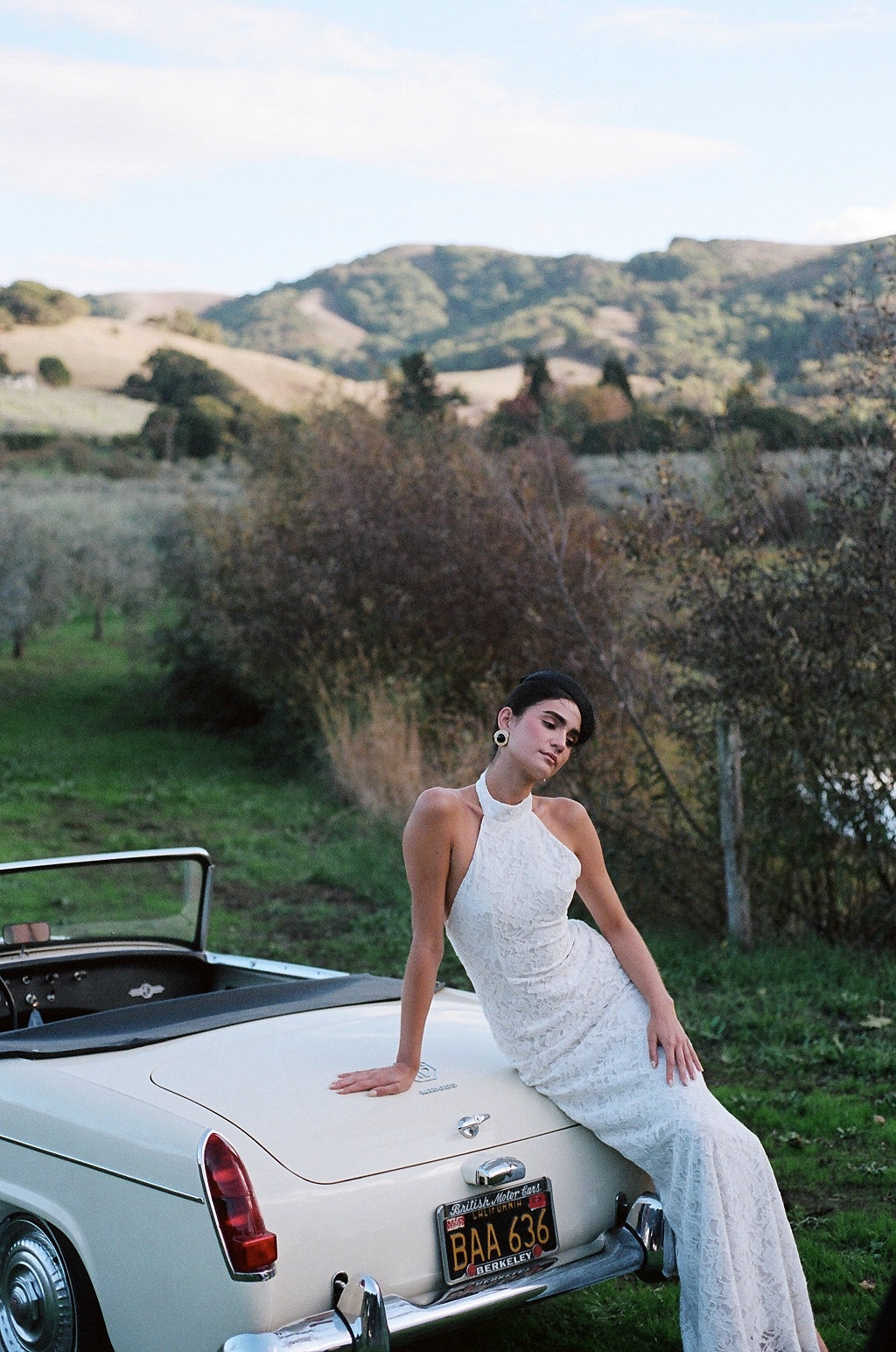 Lace High Neck white dress worn by model next to vintage car.