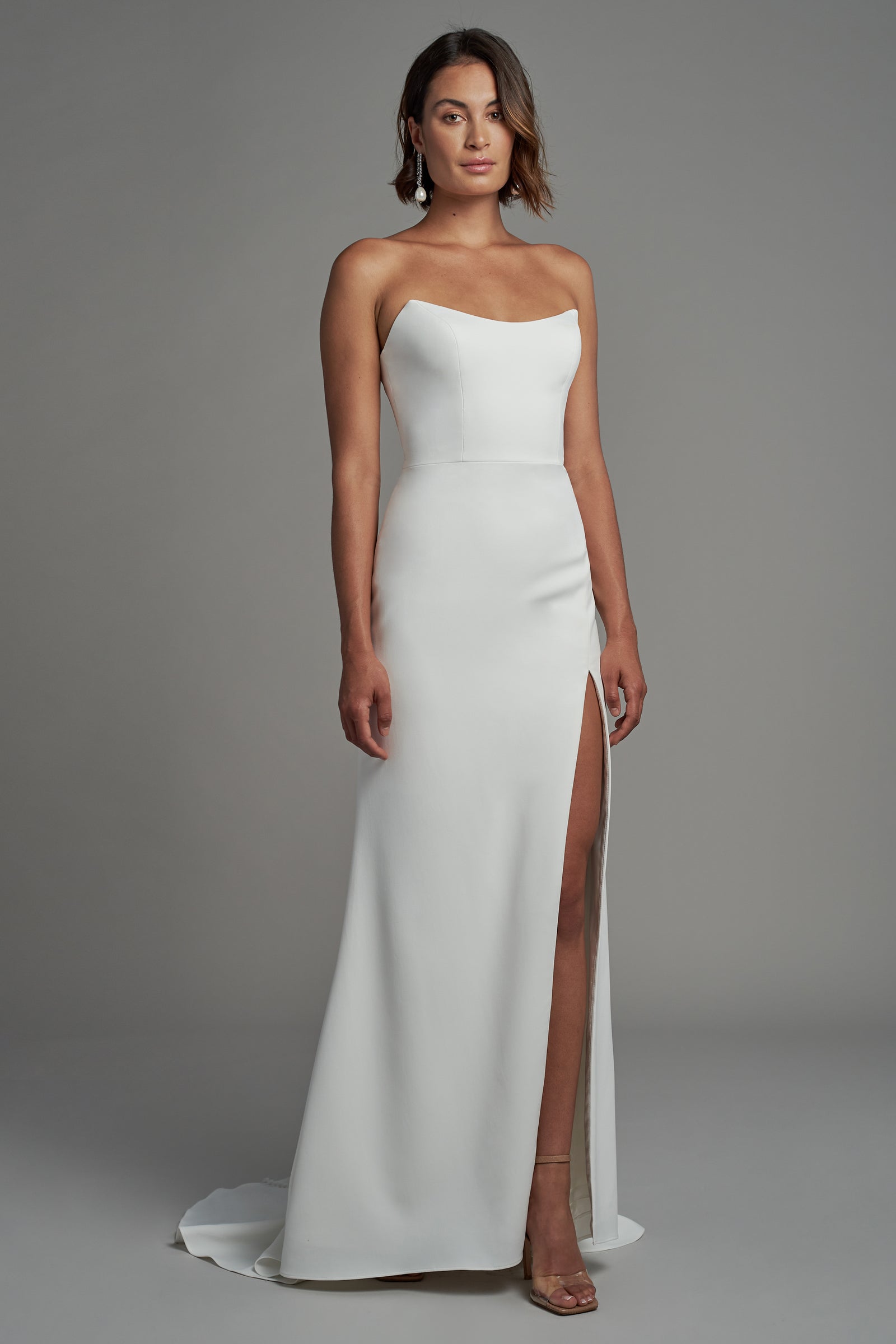 Strapless fit anf flare and column minimalist wedding dress with slit on model.