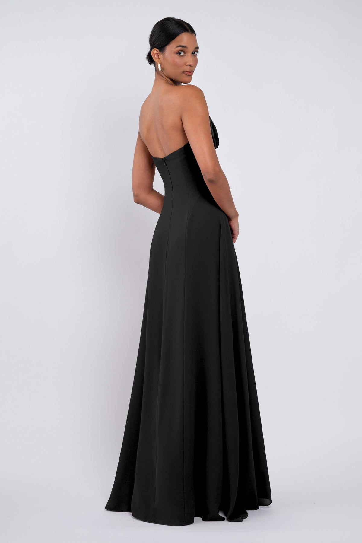 Woman wearing a black strapless gown on a white background
