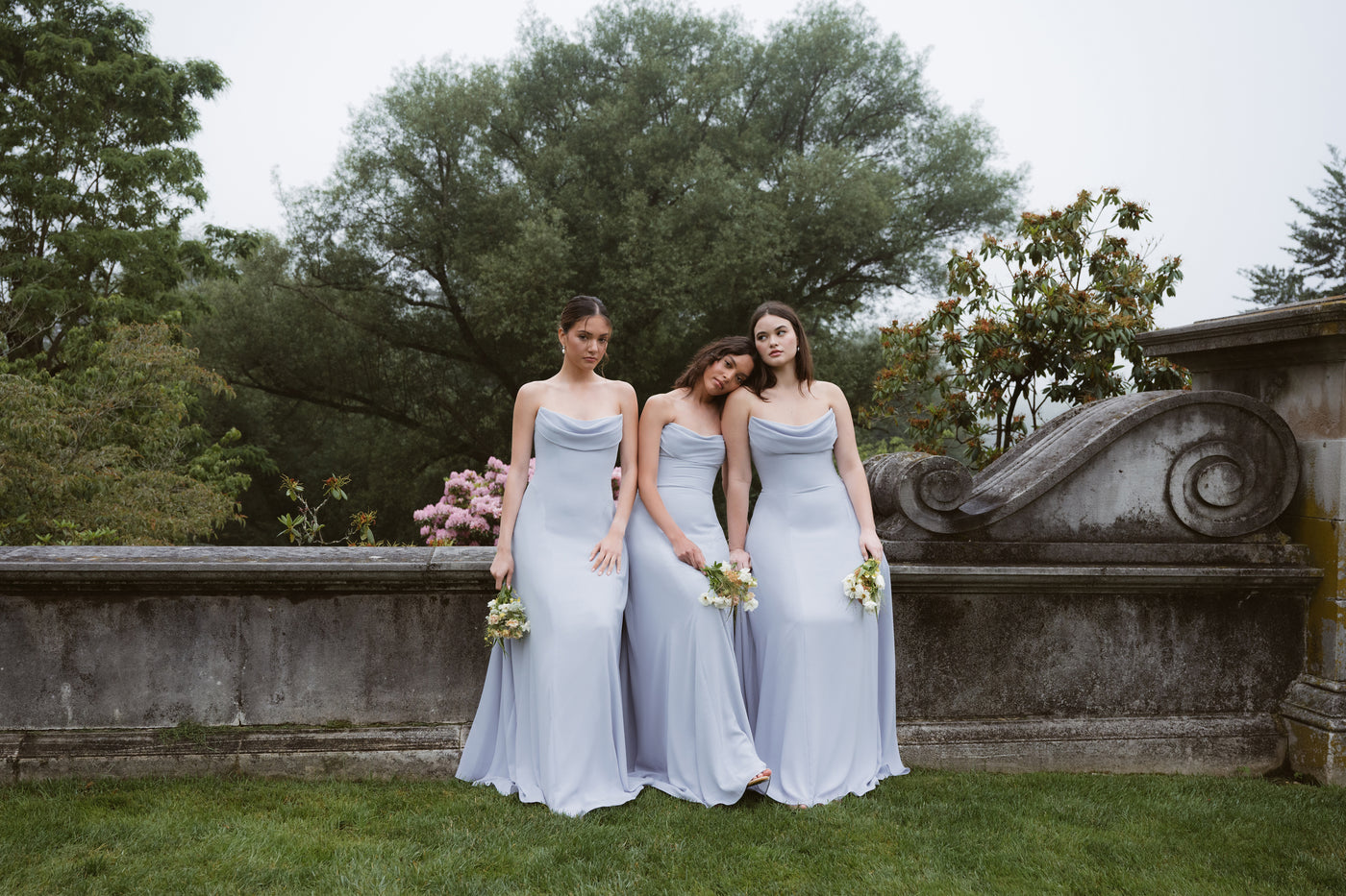 Three bridesmaids in light whisper blue bridal party dresses in crepe, strapless full length gowns.