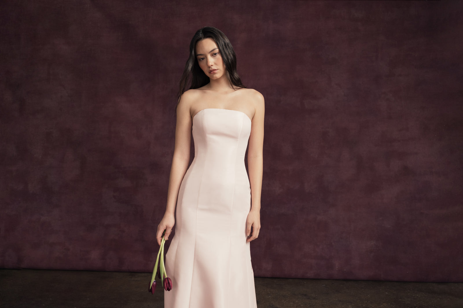 Model wearing light pink fit and flare, strapless floor length black-tie gown.