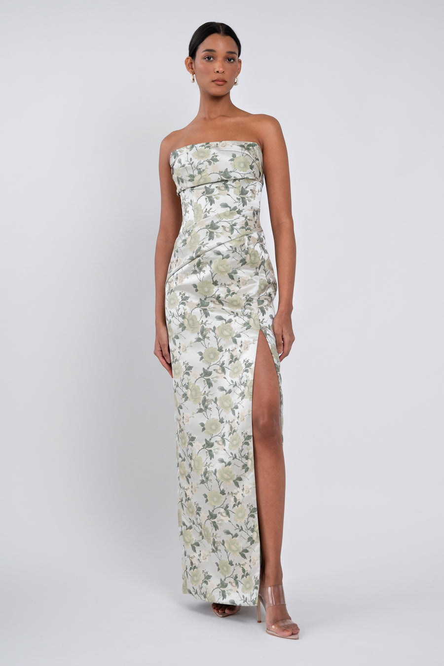 Woman wearing a strapless floral dress with a slit on a white background