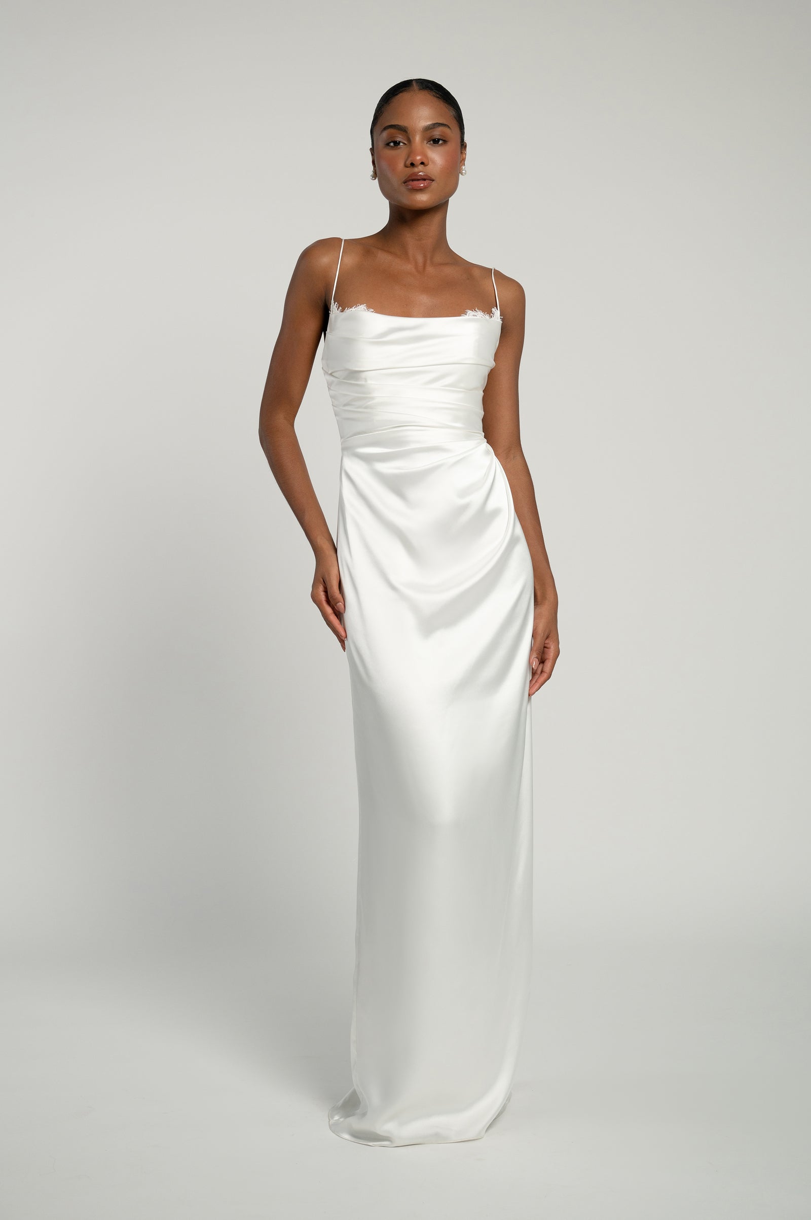 Bridal dress in slim satin silhouette with lace details and thin straps.