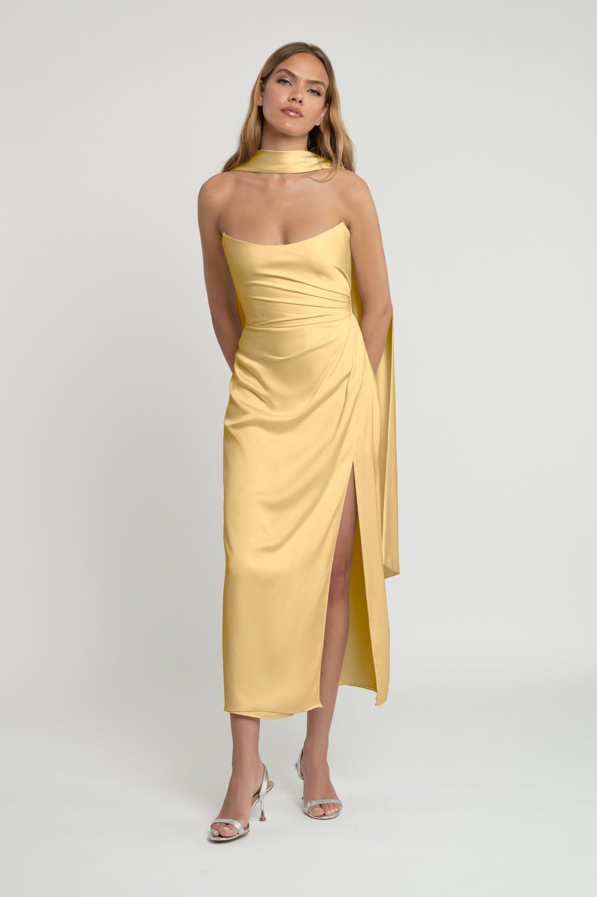 Woman wearing a yellow strapless dress with a slit on a white background