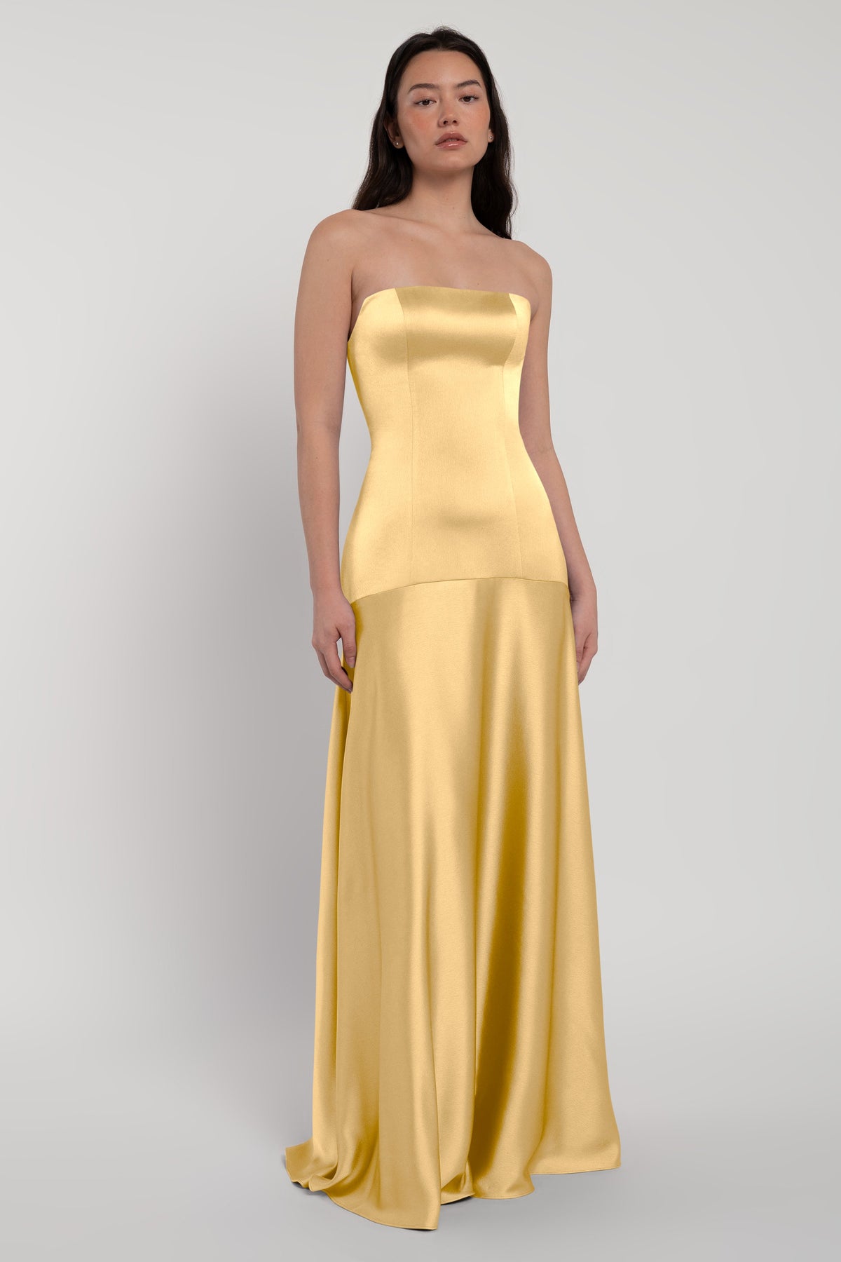 Woman wearing a strapless gold gown on a white background