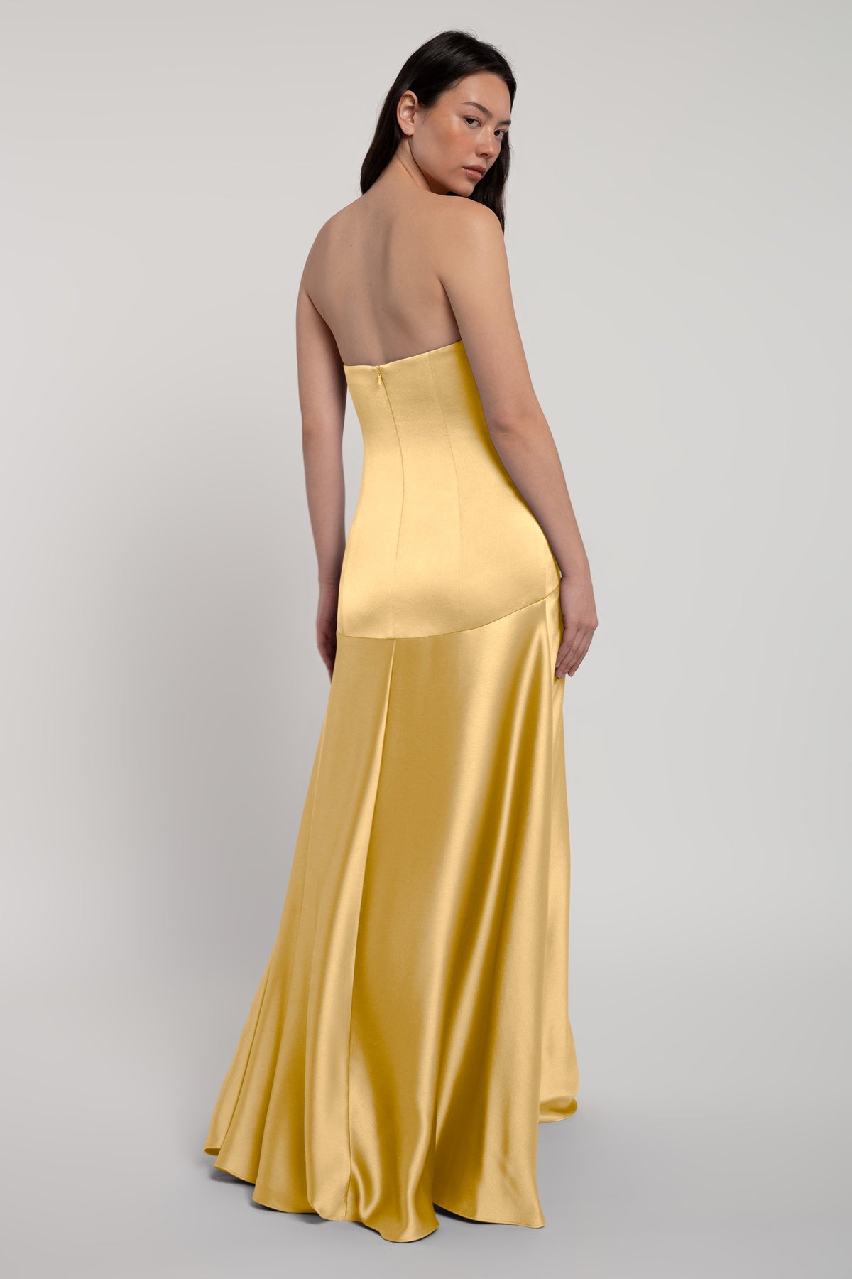 Woman wearing a yellow strapless gown on a light gray background