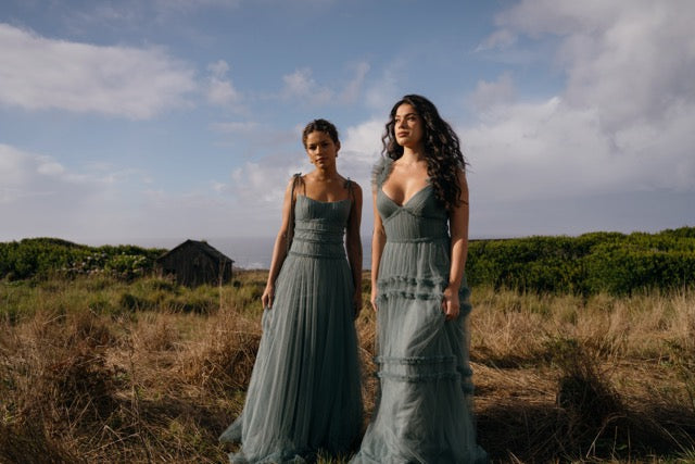 Two bridesmaids in field on coast wearing deep eucalyptus green bridesmaid dresses in tulle.