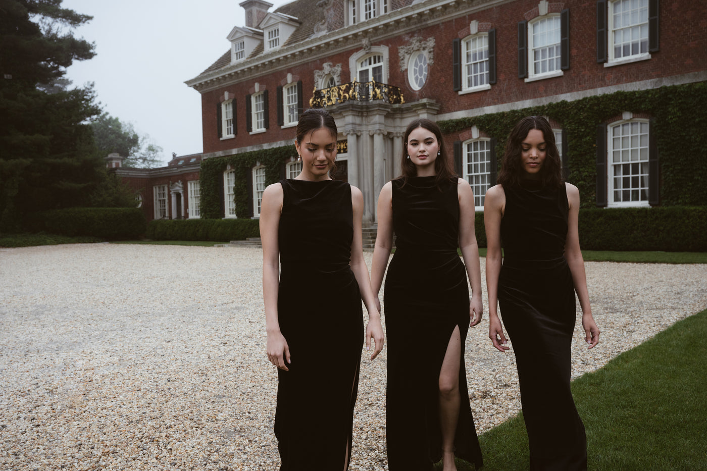 Three bridesmaids in black velvet bridesmaid dresses in front of large stately long island mansion.