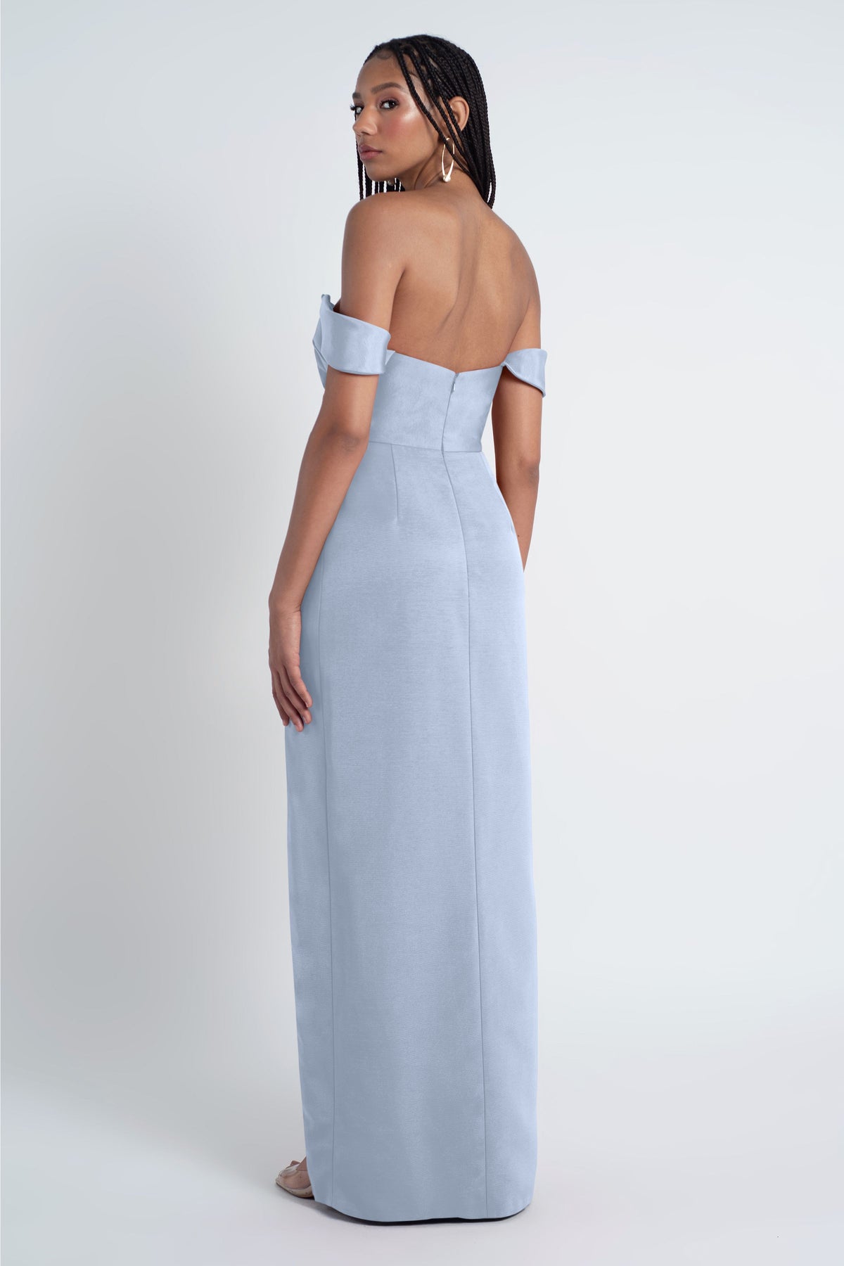 Woman wearing a light blue off-shoulder gown on a white background