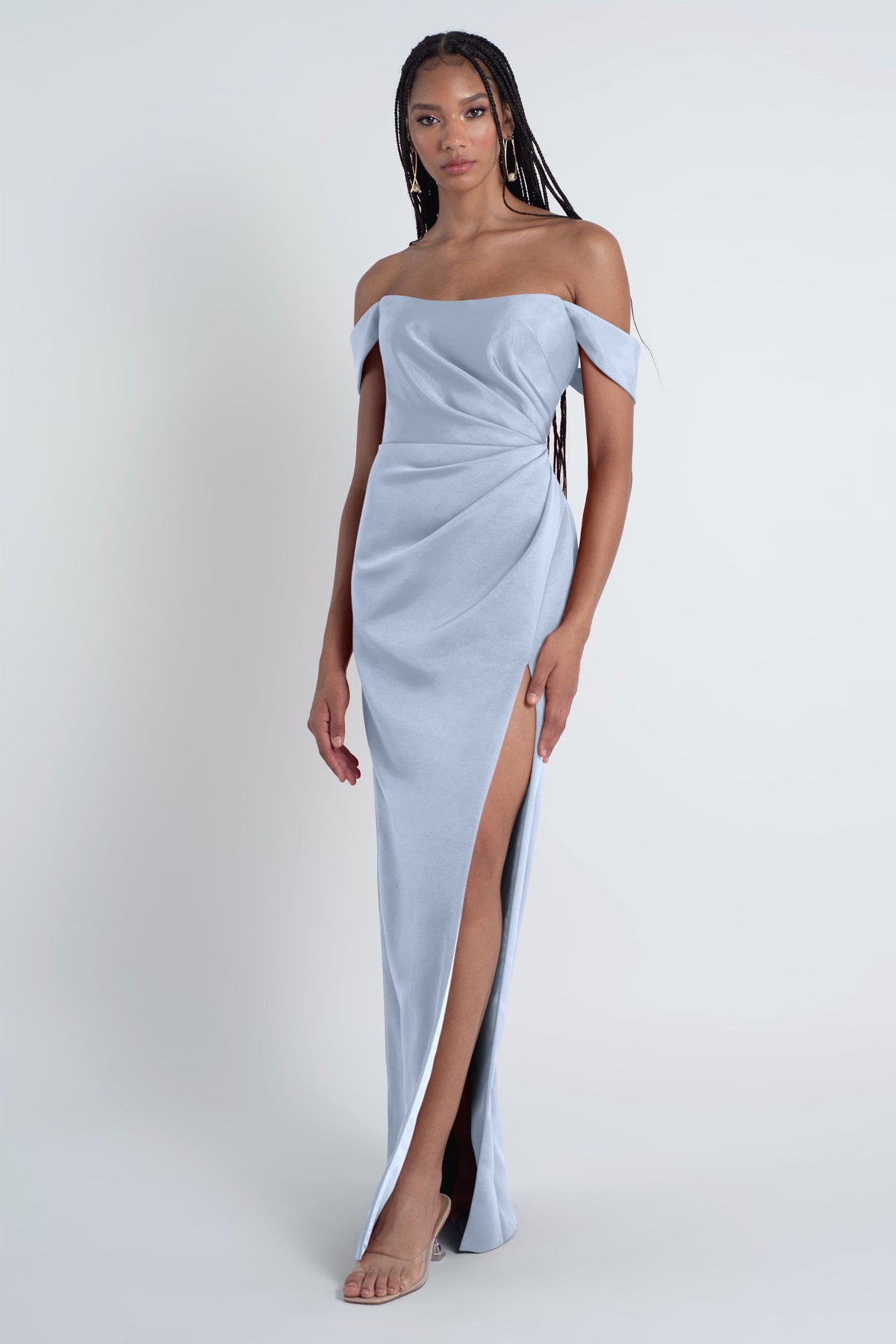 Woman wearing a light blue off-shoulder gown with a slit on a white background